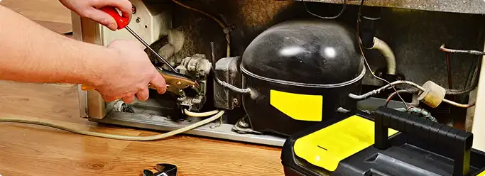 Refrigerator repair technician fixing the compressor and wiring in North Little Rock, AR