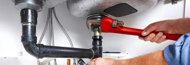 Garbage disposal repair technician tightening the sink drain and disposal connection in Little Rock, AR
