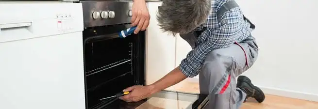 Oven repair technician inspecting and servicing an electric oven in Little Rock, AR